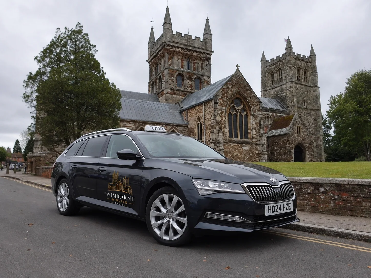 Black branded taxi with Wimborne Minster behind it